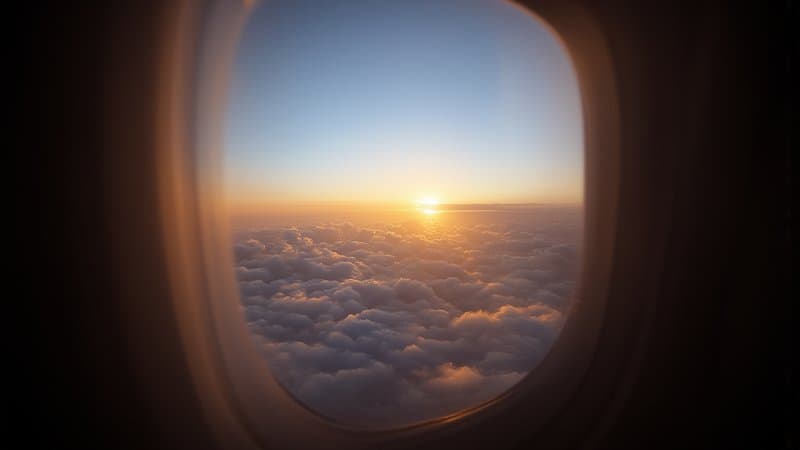 Janela de avião ao amanhecer acima das nuvens