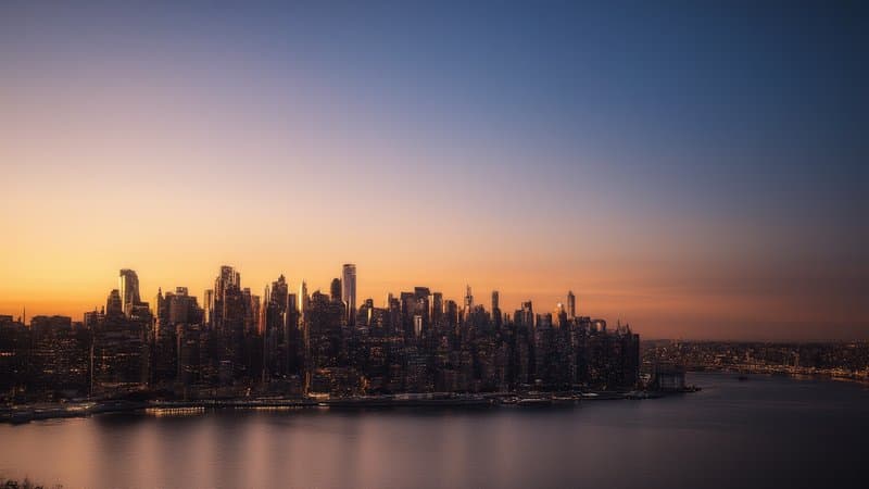 Skyline de Manhattan ao entardecer com luzes acendendo